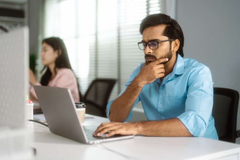 Soar man focused on laptop with hand on chin contemplating