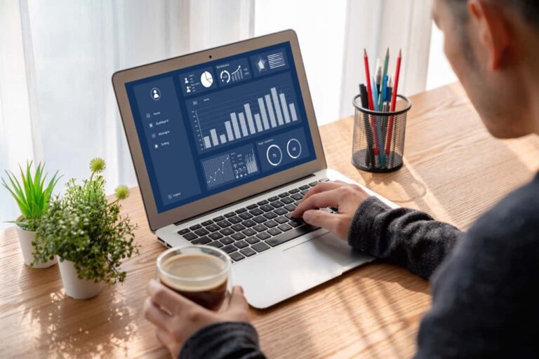 Soar man sitting at table with cup of coffee viewing website analytics on laptop