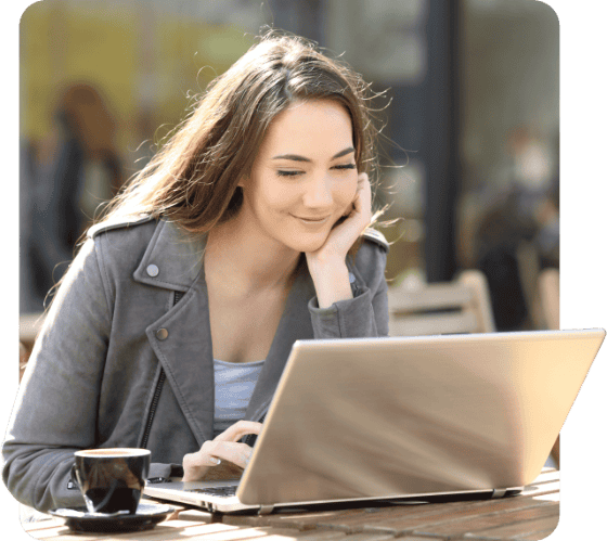 Happy Girl Using Laptop On Table With Coffee