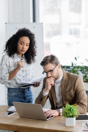 Portrait photo example: two coworkers reviewing notes at a laptop