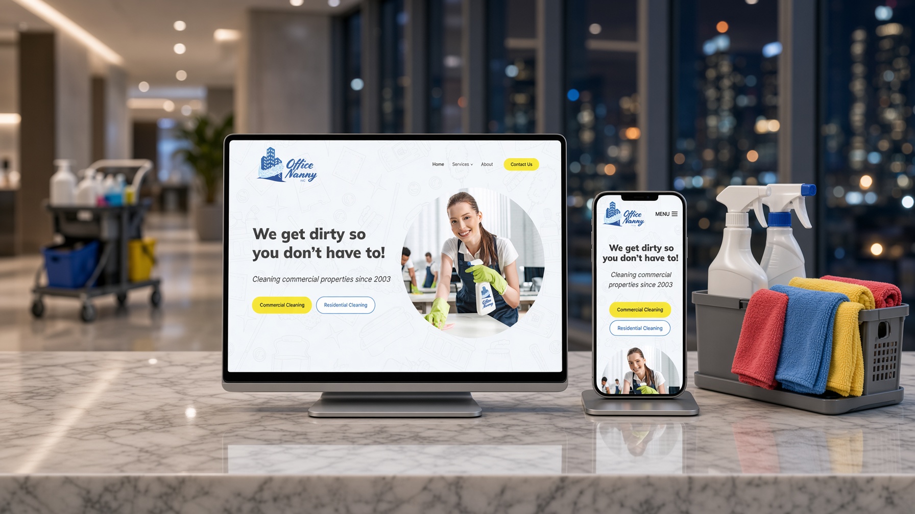 Office Nanny website on a monitor and phone on a marble reception desk beside a cleaning caddy, with city lights behind